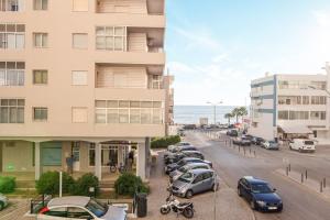 a row of cars parked in a parking lot next to a building at Modern Apartment by the Sea in Quarteira