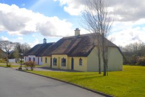 une maison jaune avec un toit marron et une rue dans l'établissement Cottage 33 Old Killarney Village Killarney, à Killarney