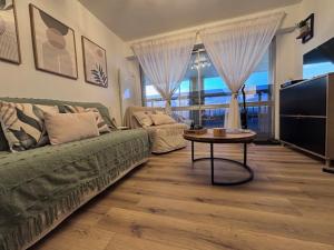 a living room with a green couch and a table at Suite GrandLarge in Berck-sur-Mer