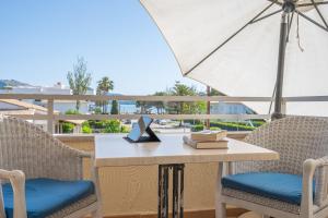 a table and chairs with an umbrella on a balcony at Veleta ll in Pollença