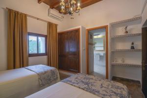 a bedroom with two beds and a window and a chandelier at Can Joan Vich I in Santa Eularia des Riu +22 photos