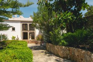 a white house with a stone wall and trees at Can Joan Vich I in Santa Eularia des Riu
