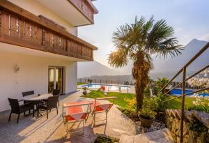 a patio with a table and chairs and a palm tree at Haus Hohenrain Ferienwohnung 1 in Schenna