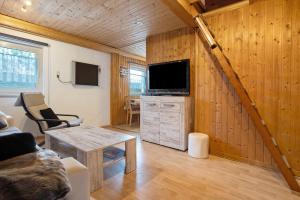 a living room with a couch and a tv at Ferienhaus Am Darß - Leuchtturm in Pruchten