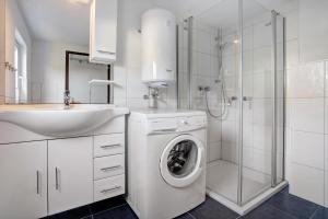 a white bathroom with a washing machine and a sink at Ferienhaus Am Darß - Leuchtturm in Pruchten +15 photos