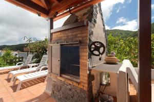 a stone fireplace on a patio with chairs on a deck at Casa Rural Medina 1 in Agulo