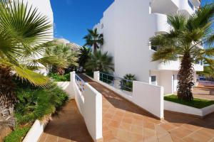 a white building with palm trees in front of it at Posidonia in Portocolom