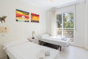two beds in a white room with a window at Keops in Oliva +19 photos