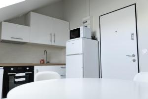 a kitchen with white cabinets and a refrigerator with a microwave at Appartement 3 morangis in Morangis