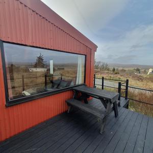 a bench sitting on the side of a building with a window at The Other Wee Red Cabin in Dunvegan