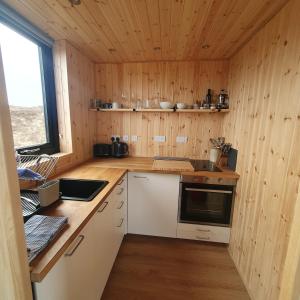 a kitchen with wooden walls and a counter with a sink at The Other Wee Red Cabin in Dunvegan