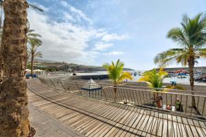 a walkway next to a beach with palm trees at La Casa de Tina in Playa de San Juan