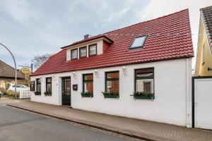 a white building with a red roof on a street at Das weiße Stadthaus in Wesselburen