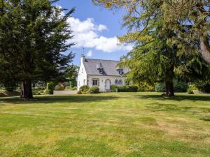 a white house with trees on a lawn at Maison familiale terrasse et parc in Plouisy