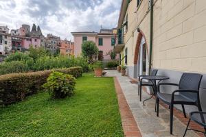 a patio with chairs and a green yard with buildings at Montemare in Ameglia