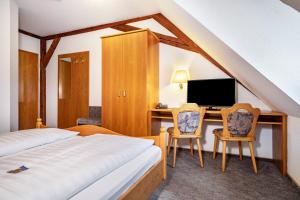 a bedroom with a bed and a desk with a computer at Gasthof Adler in Ebenweiler