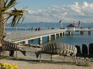 a bench on the beach next to a pier at Ferienwohnung Kobl in Immenstaad am Bodensee