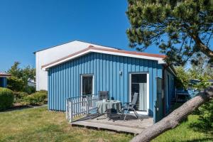 a blue shed with a table and a chair on a deck at Möve Aba Bungalow 61 in Rerik