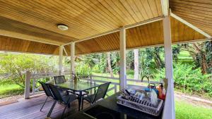 a screened in porch with a table and chairs at EVASION Bungalow Harmonie in Sarraméa