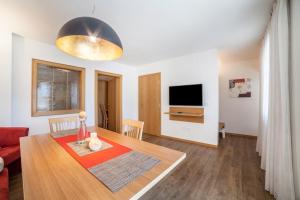 a living room with a table and a tv at Schnitzer Ferienwohnung Anemone in Rablà