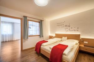 a bedroom with a large bed with red blankets on it at Schnitzer Ferienwohnung Anemone in Rablà