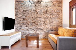 a living room with a stone wall with a couch and a table at La Tirajanera 1 in Vega de San Mateo