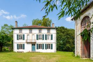 an old house with a balcony on a grass field at Maison Etxeparea in Ustaritz
