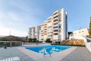 an apartment with a swimming pool in front of a building at Los acantilados in Almería