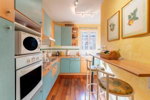 a kitchen with blue cabinets and a counter with stools at Appart face au Palais des Papes in Avignon