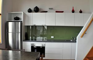 a kitchen with white cabinets and a stainless steel refrigerator at Triggerplant 3 in Dinner Plain +7 photos