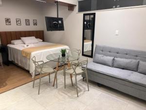 a bedroom with a bed and a table and a couch at Suites Coliseu 40-A in Petrolina +8 photos