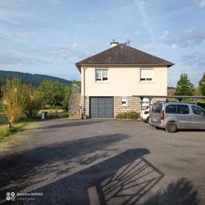 a house with a car parked in a parking lot at La Clematite d'Olt in Saint-Côme-dʼOlt
