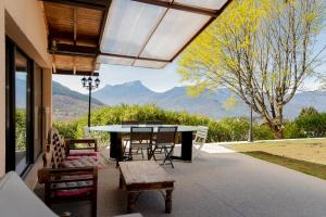 a patio with a table and chairs and mountains at Maison avec Piscine, Spa et Jacuzzi in Saint-Jean-dʼArvey