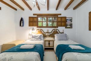 two beds in a room with white walls and wooden ceilings at Kety in Serdió