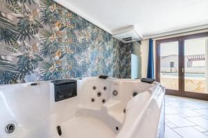 a bath tub in a bathroom with a tropical wallpaper at Pretziosa in Castiadas +34 photos