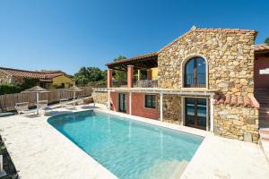 a swimming pool in front of a stone house at Pretziosa in Castiadas