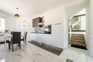 a kitchen with white cabinets and a table with chairs at Villa Leon with Private Pool in Quartu SantʼElena