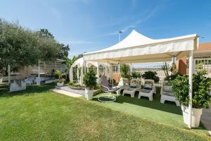 a white gazebo with chairs and tables in a yard at Villa Leon with Private Pool in Quartu SantʼElena