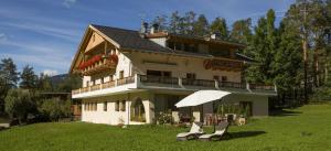 a large house with two chairs and an umbrella at Runcac Apt Pla in San Vigilio Di Marebbe