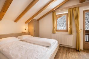 a bedroom with a white bed and a window at Runcac Apt Pla in San Vigilio Di Marebbe