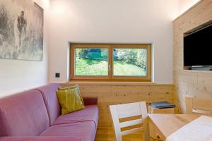 a living room with a purple couch and a table at Baumannhof Villnöß in Funes
