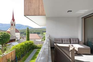 a balcony with a couch and a view of a church at Appartement Sonnlicht Pfalzen in Falzes