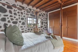 a bedroom with a bed with a stone wall at El Rincón de Guatisea in San Bartolomé
