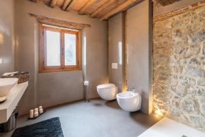 a bathroom with two toilets and a stone wall at Casa Biffoli - Bucine in Bucine
