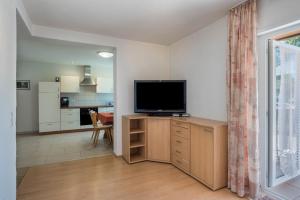 a living room with a flat screen tv on a wooden cabinet at Haus Isele in Urberg