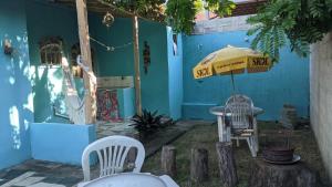 a blue building with a table and chairs and an umbrella at Kitinete e suite Recanto do Bem-te-vi in Serra