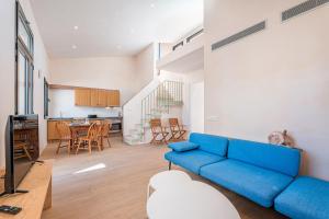 a living room with a blue couch and a kitchen at Casa La Mar in Santanyi