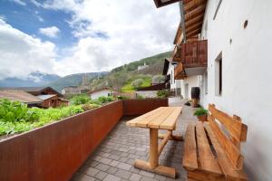 a wooden bench sitting on a patio with a view at Ferienwohnungen Zwick Valarga in Malles Venosta