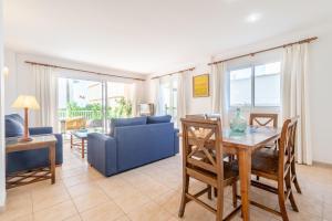 a living room with a table and a blue couch at Talaia Bajos A in Port de Pollensa