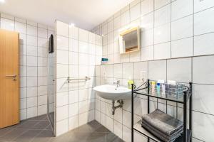 a white tiled bathroom with a sink and a mirror at Eifel im Herzen in Hambuch +23 photos